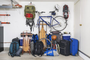 A lot of different sport equipment stored against a wall